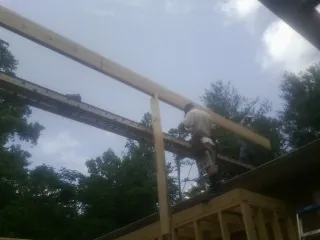 Carpenter setting a ridge beam over a new addition frame — Ice Dam Removal by Roofing Brothers in Foley
