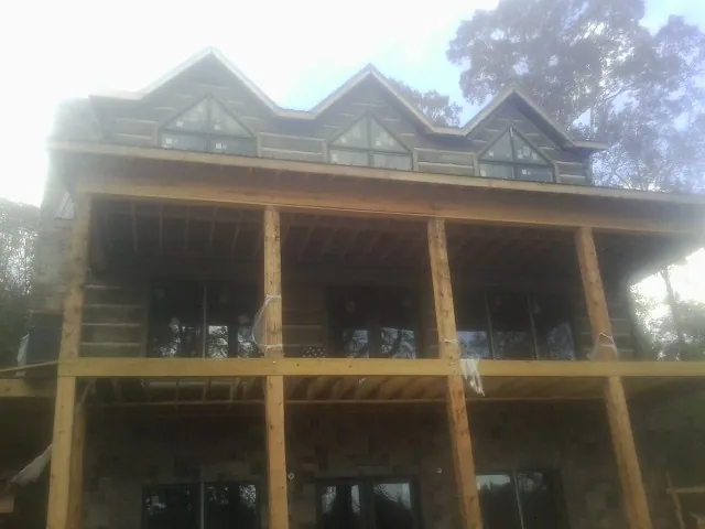 Dormers and porch framing on a large log home under construction — Roof Coating work by our crew in Foley